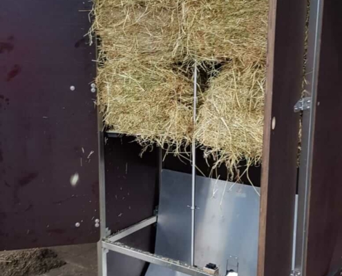 Innenansicht einer Portionsraufe mit gefüllten Heuballen, automatische Fütterung für Pferde