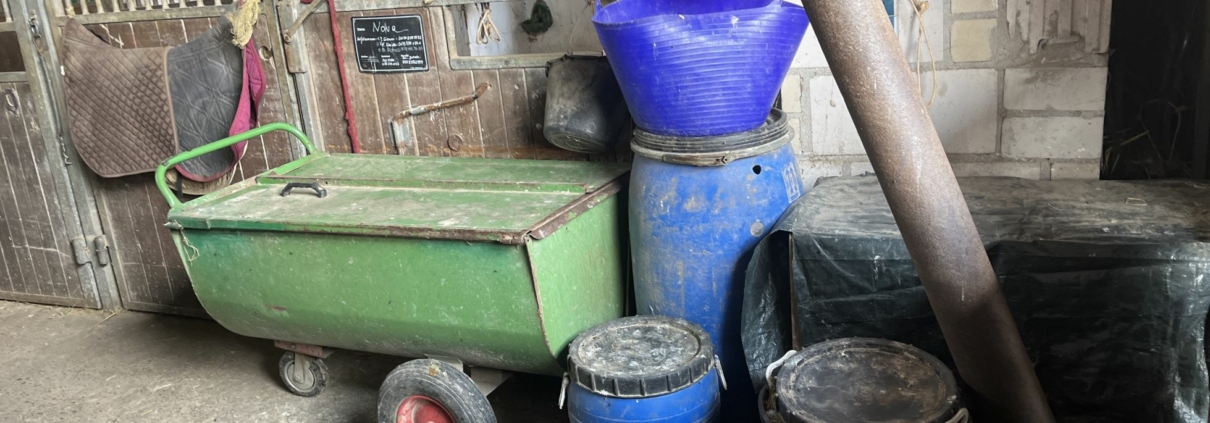 Chaotische Futterkammer mit Futtersäcken, Schüsseln und Messbechern – automatische PowerFeeder sorgen für sichere, stressfreie und staubfreie Pferdefütterung im Stall